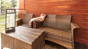 A wicker sofa with a cushion and a throw blanket against a wooden wall. - Sopot Marina (Sopot)
