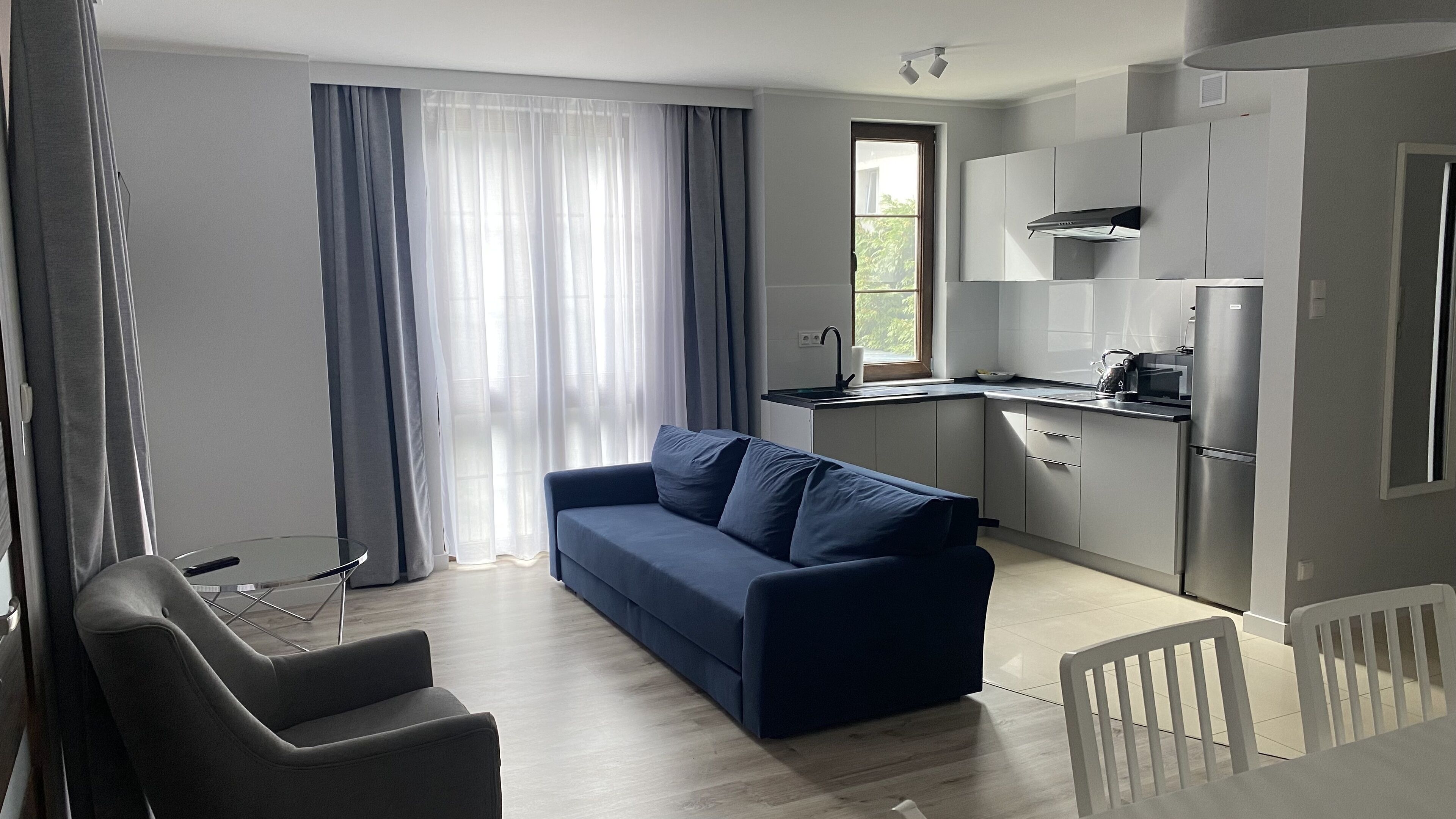 Un salon moderne comprenant un canapé, une table à manger et un coin cuisine avec un réfrigérateur et une cuisinière.