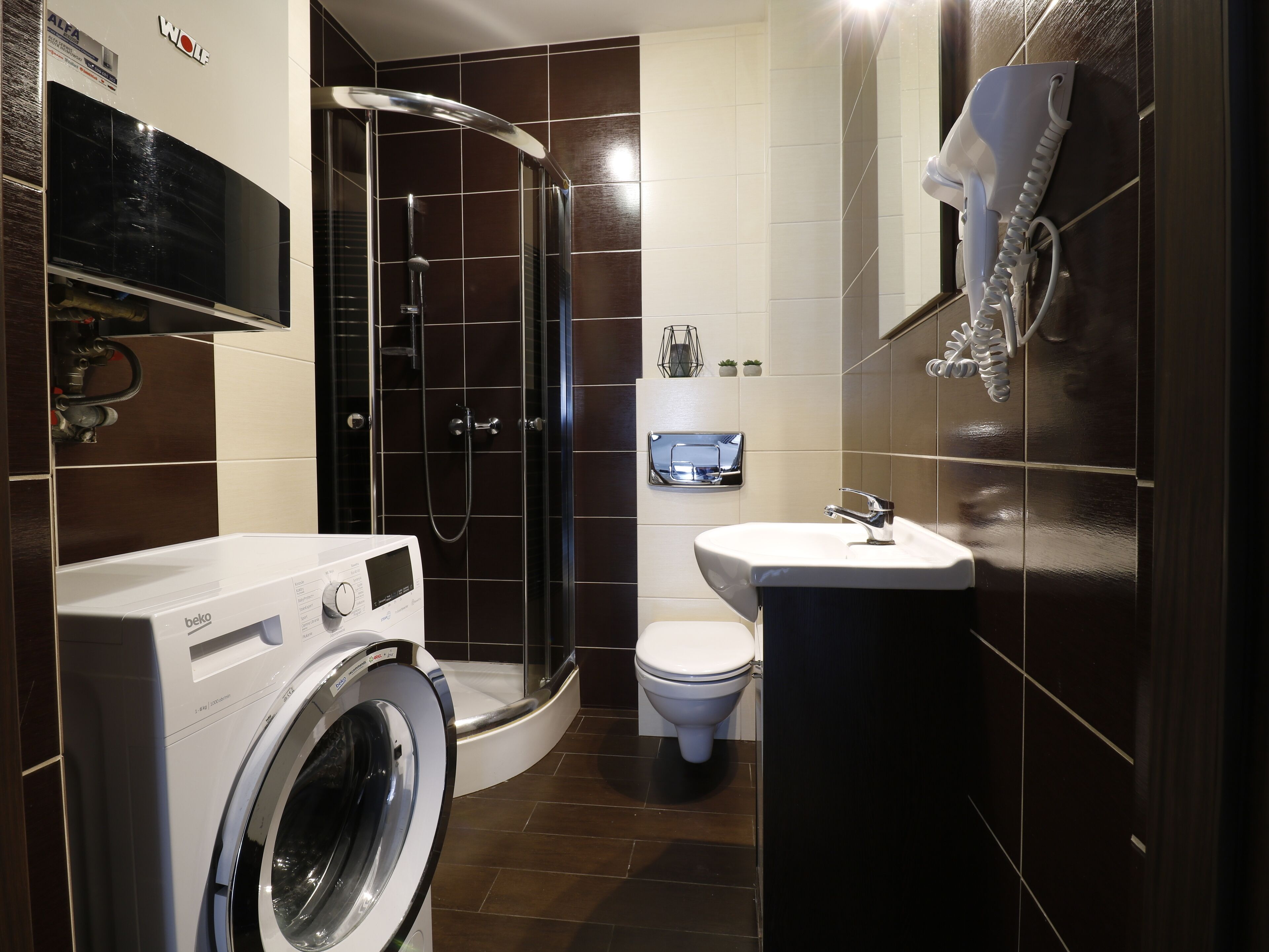 Een kleine badkamer met een wasmachine, toilet, wastafel en douchecabine.