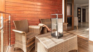 A corner of a room with wooden panel walls, wicker furniture, and a glass table with a metal frame. - Sopot Marina (Sopot)