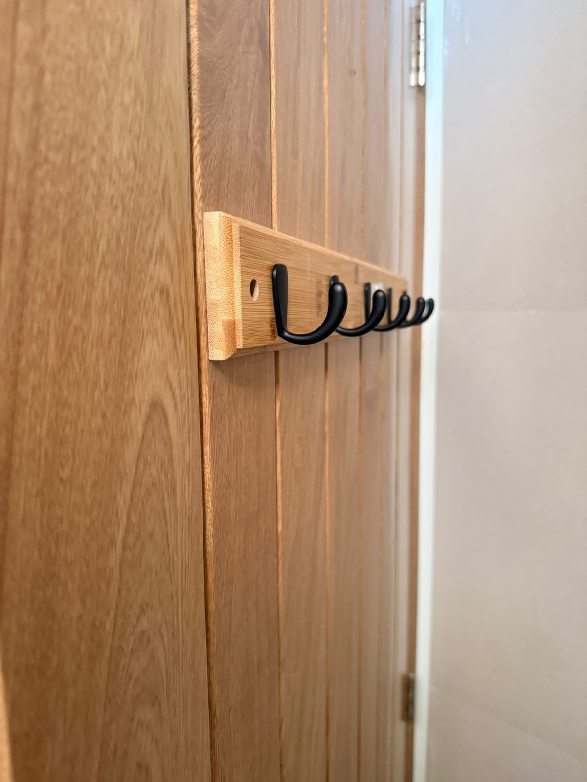 Una puerta de madera con un panel de ganchos metálicos negros.