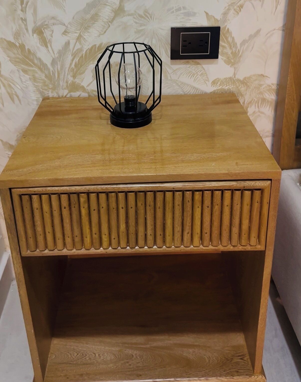 A wooden nightstand with a textured front panel and a glass enclosure on top.