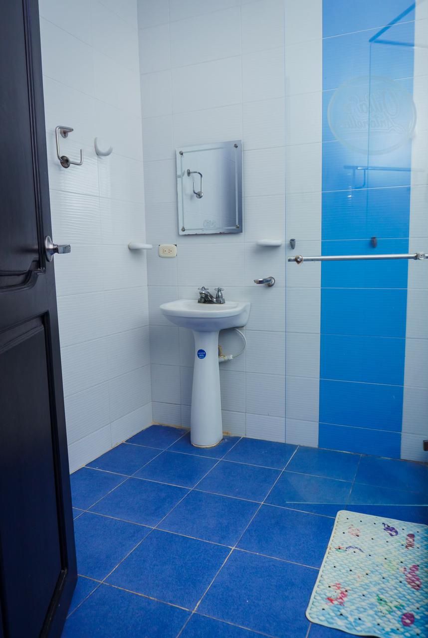 A bathroom with a white sink, blue tiles, a door, and a mat on the floor.