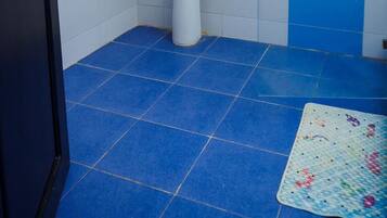 A bathroom with a white sink, blue tiles, a door, and a mat on the floor.
