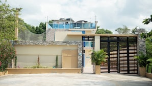 Un edificio moderno con entrada protegida, un espacio exterior cubierto y una terraza con paneles solares.