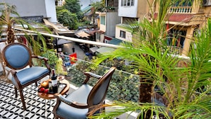 A balcony with two chairs, a table, and a bottle of wine. - HANZ Hotel Memory Hanoi (Hanoi)