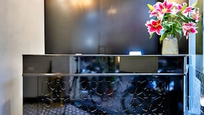 A reception area with a black wall displaying clocks for Tokyo, New York, Paris, and London. A vase with pink flowers is on the counter. - HANZ Hotel Memory Hanoi (Hanoi)