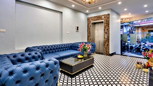 A modern living room with a blue sofa, a coffee table, and a patterned floor. - HANZ Hotel Memory Hanoi (Hanoi)