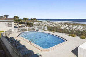 Relax by the pool with ocean views, surrounded by lounge chairs and a small table.