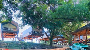 A riverside area with kayaks and a wooden structure with elevated seating. - Son's Rio Cibolo - Glamping Cabin G (Marion)
