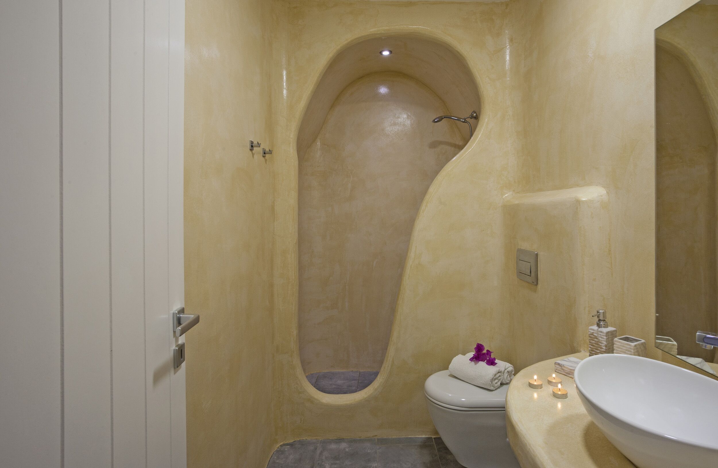 A bathroom with a unique bathtub design, a toilet, and a sink with candles.