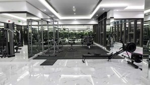Un gimnasio moderno con paredes espejadas, diversos equipos de ejercicio y un piso de mármol pulido.