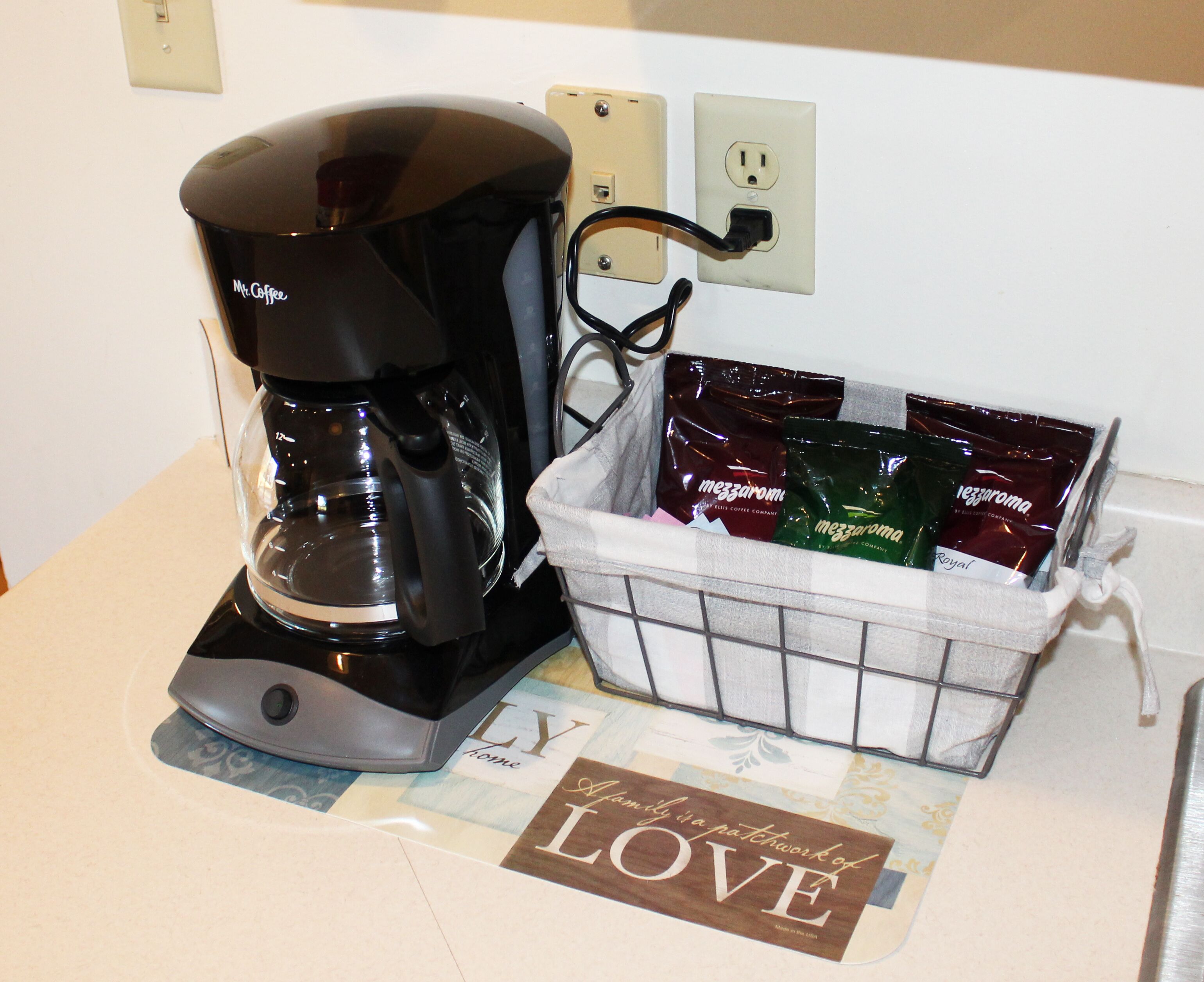 A coffee maker and a basket of coffee pods on a countertop.