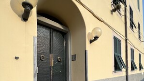 Een gebouw met een dubbele deur, treden die naar de ingang leiden en een lamp aan de muur.