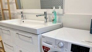 Een moderne badkamer met een ingebouwde wasmachine, een wastafel en een spiegel.