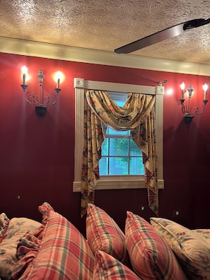 A room with a window, floral curtains, and wall-mounted sconces. - Spacious Colonial Home with Sunroom, Jacuzzi & Single-Level Living (Van Lear)