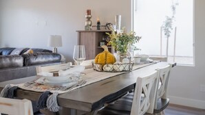 A dining area with a table set for two, a decorative pumpkin centerpiece, and a view of the outdoors through a large window. - So Zion Painted Desert-4Bed, 3Bath, Hot Tub, Deck (Hildale)