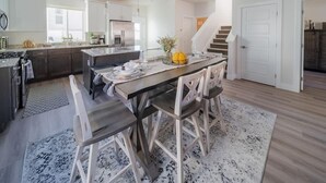 A modern kitchen with a central island, dark cabinetry, and a dining area with a wooden table and chairs. - So Zion Painted Desert-4Bed, 3Bath, Hot Tub, Deck (Hildale)