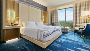Habitación de hotel moderna con una cama grande, un escritorio, una silla y vistas al exterior.