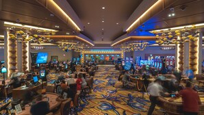 Un casino con múltiples mesas de juego y máquinas tragamonedas, un área de Servicios al Jugador y una alfombra vibrante con diseños.