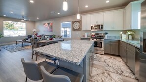 Una cocina moderna con encimeras de granito, electrodomésticos de acero inoxidable y un área de comedor con una isla grande.