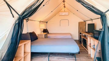 Une tente équipée d’un lit, d’un bureau et d’une télévision.