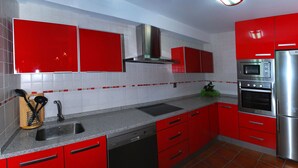 A kitchen with red cabinets, a stainless steel refrigerator, and a built-in oven. - Rural house in Navarra for children and dogs for 8-10 people (Eulz)