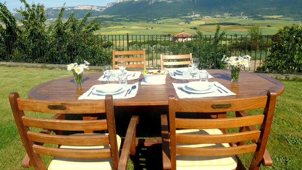 A round wooden table set for two with a view of a mountainous landscape. - Rural house in Navarra for children and dogs for 8-10 people (Eulz)