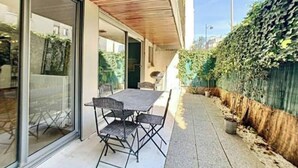 Une terrasse avec une table et des chaises, une porte-fenêtre coulissante et un plafond en bois.