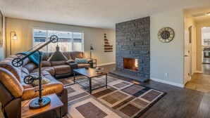A living room with a stone fireplace, leather sofa, and a coffee table. - The Industrial - Pet Friendly Home with Garage by Boise Fairgrounds (Boise)