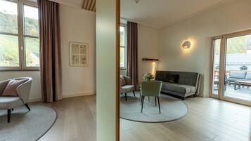 A spacious living room with a sofa, chairs, a coffee table, and a large window with curtains.