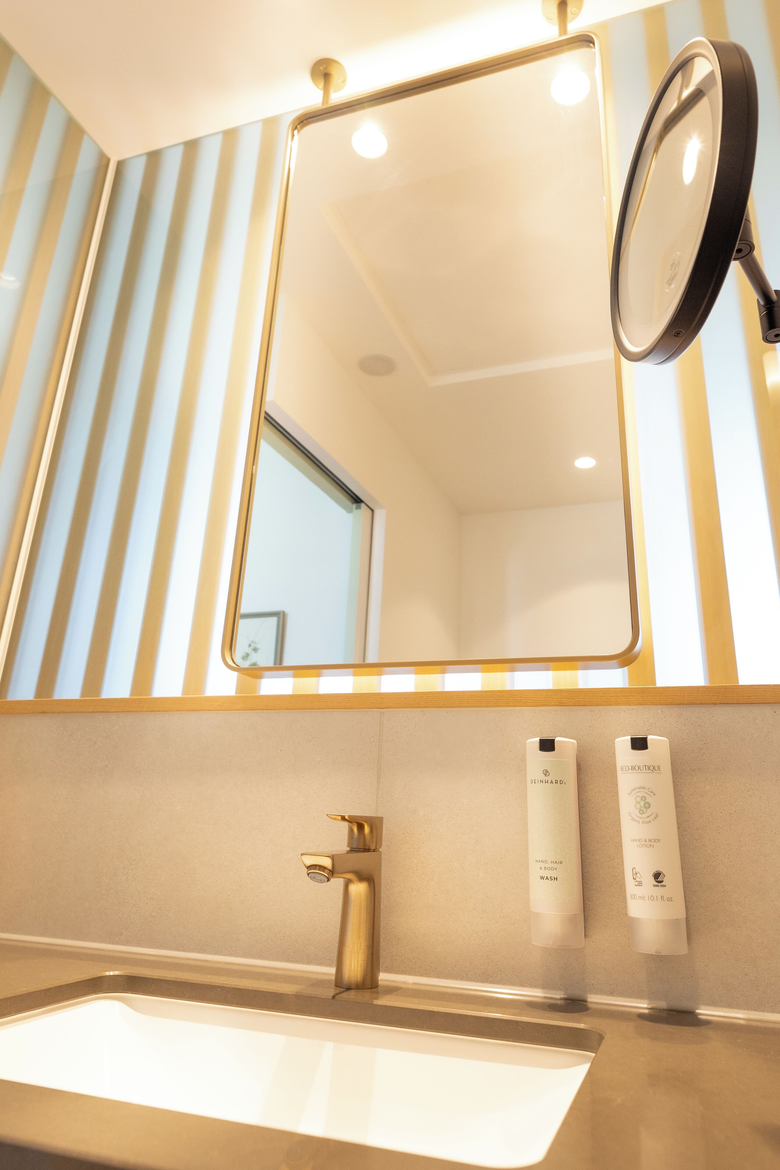 A bathroom with a sink, mirror, and two toiletry bottles.