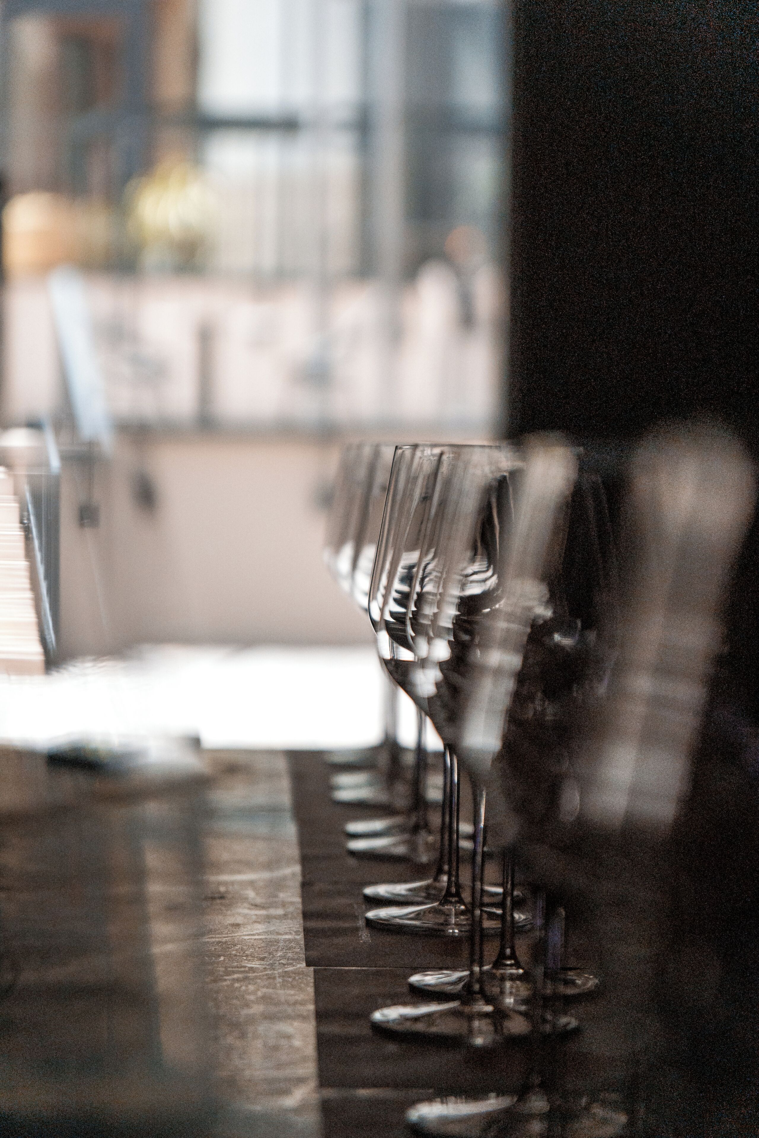 A bar with multiple wine glasses lined up on a reflective surface.