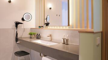 A modern bathroom with a large mirror, a hairdryer, a sink, and a small stool.