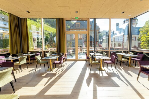 A spacious indoor dining area with large windows, wooden flooring, and a variety of seating options. - DEINHARD's (Bernkastel-Kues)