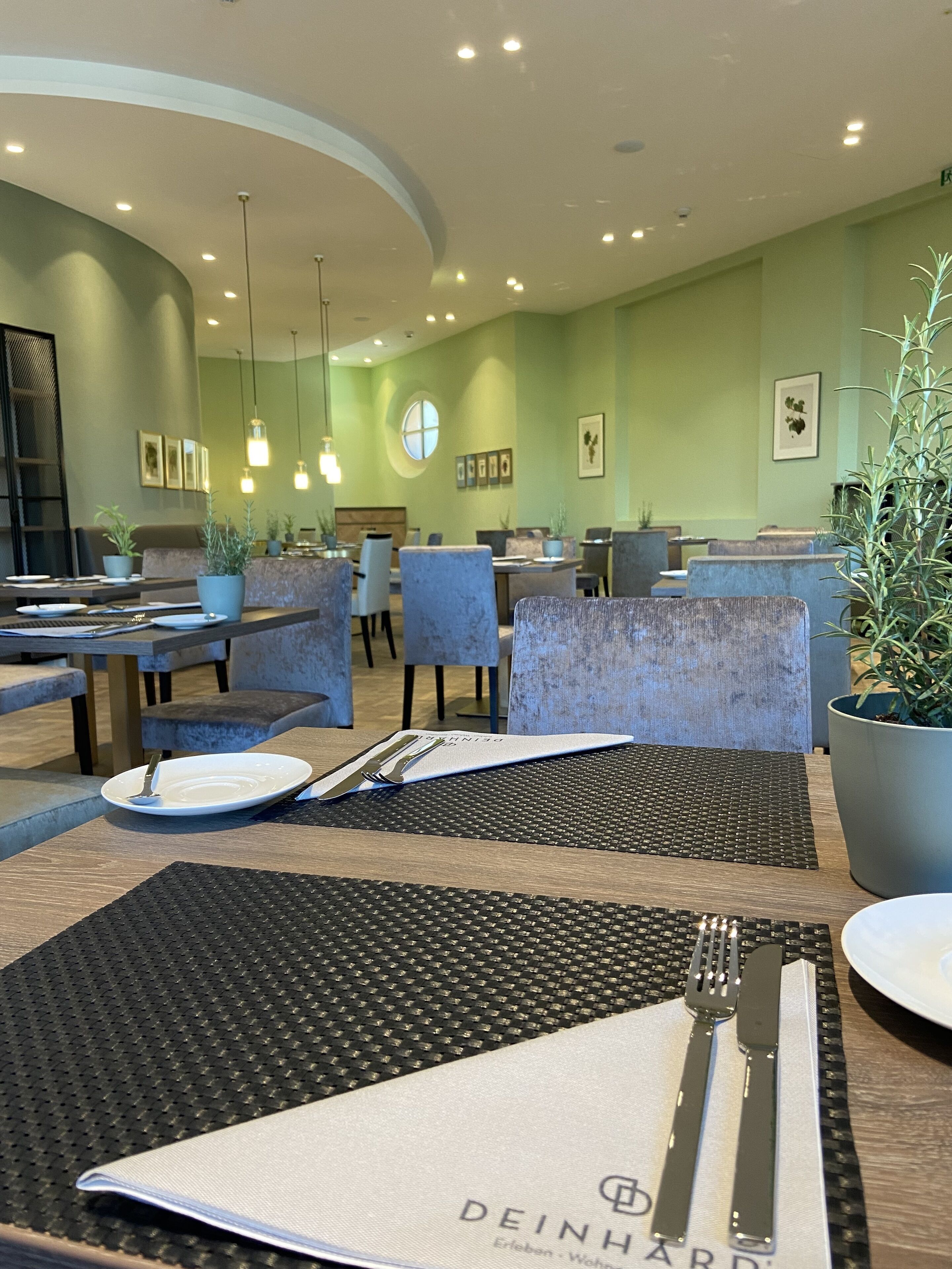Un restaurante con una decoración moderna, con mesas redondas, manteles individuales negros, sillas y lámparas colgantes.