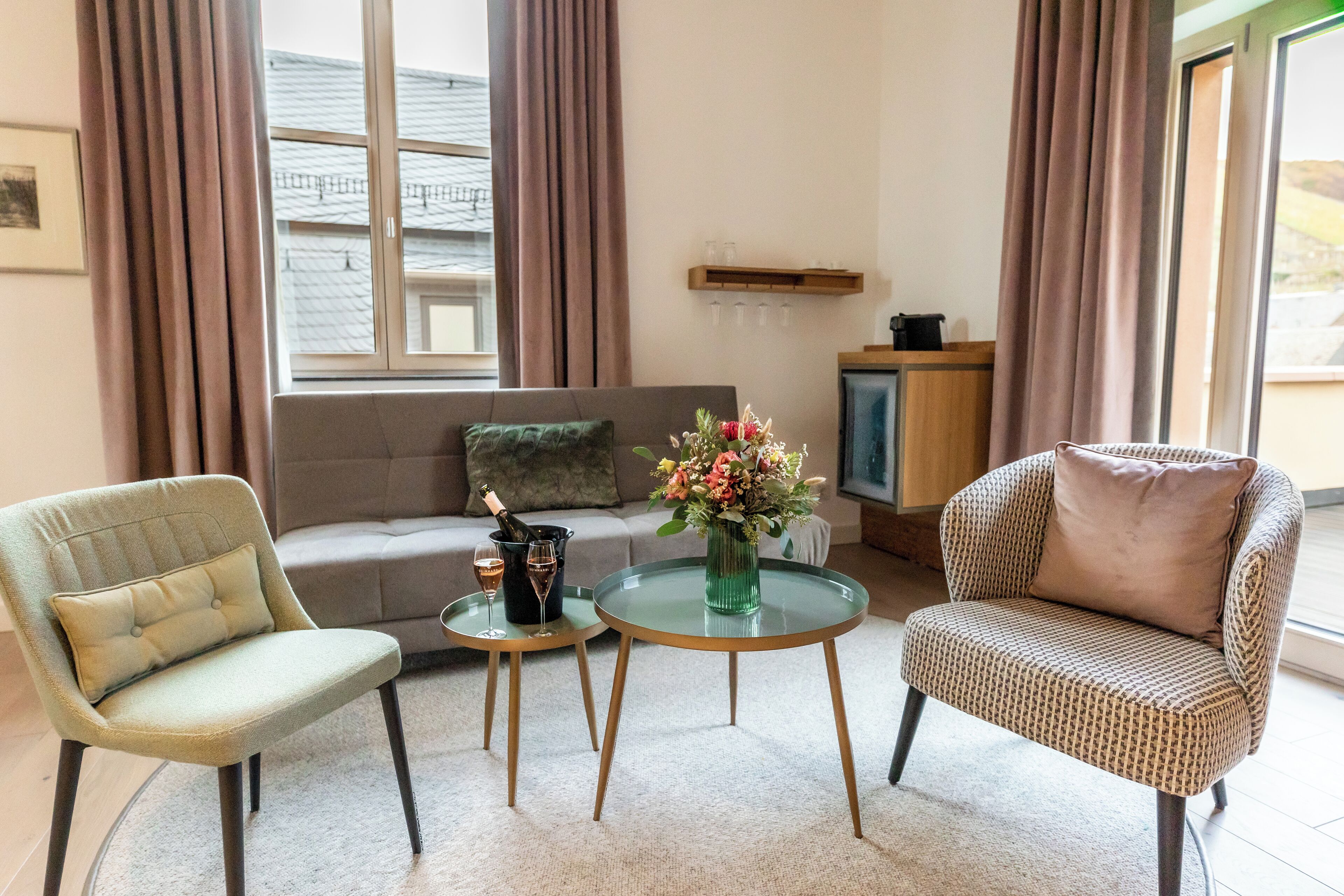Una sala de estar con un sofá, dos sillones, una mesita con un florero y un televisor.