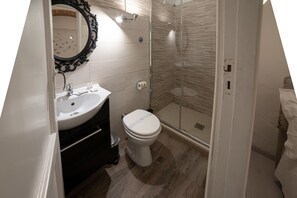 A bathroom with a white sink, toilet, and glass shower enclosure. - Beautiful apartment in the heart of Florence (Firenze)