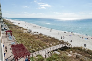 A beach with a wooden walkway leading to a red-roofed structure. - Majestic Tower 2-502 with RESERVED PARKING SPACE (Panama City Beach)