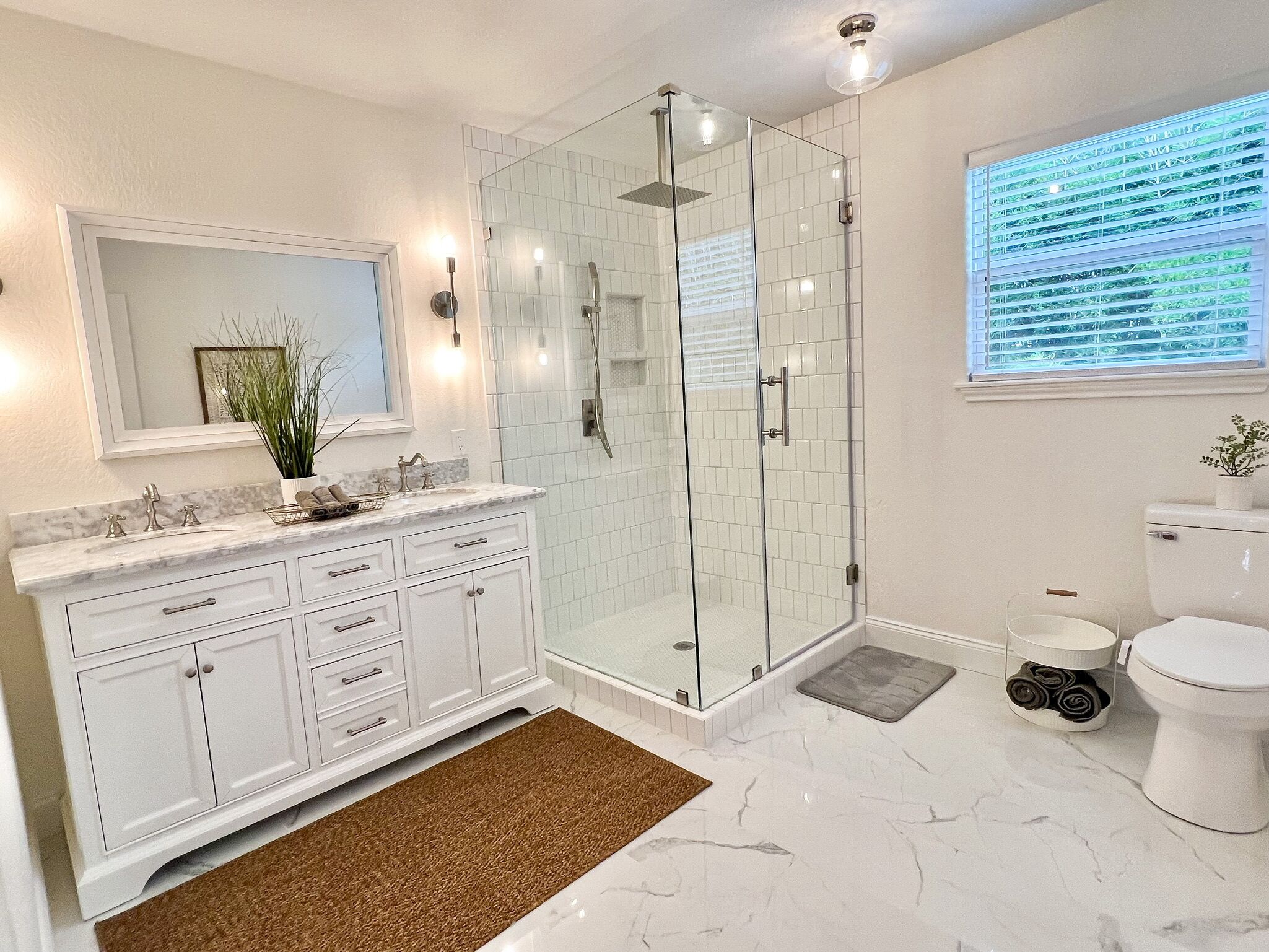 A modern bathroom with a glass-enclosed shower, a white toilet, and a marble sink.