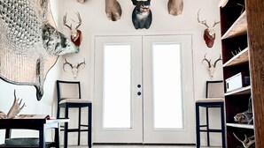 Una stanza con un tappeto grande, travi in legno al soffitto e teste di animali appese al muro.