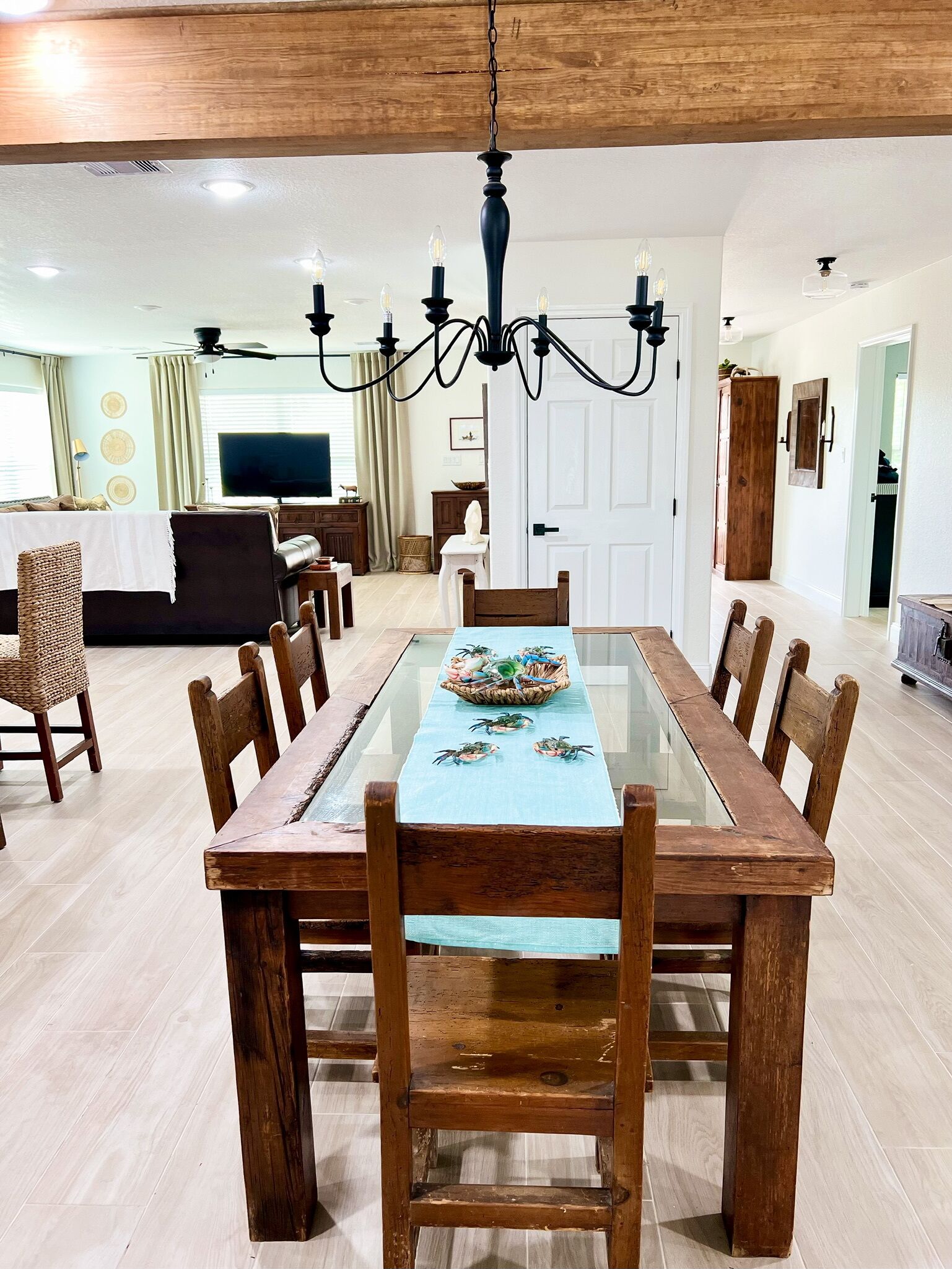 A dining area with a long wooden table, chairs, and a chandelier.