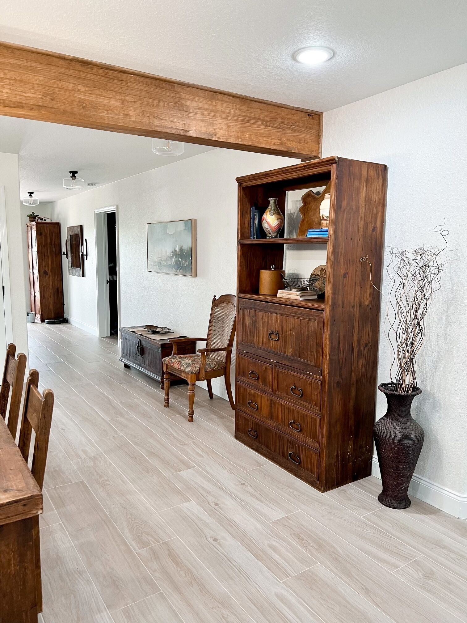 Un coin repas comprenant une table en bois, des chaises, un buffet et un vase.