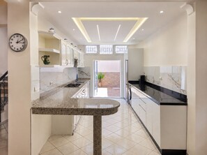 A modern kitchen with a central island, white cabinetry, and a clock on the wall.