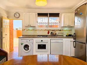 A kitchen with white cabinets, a washing machine, an oven, and a refrigerator.