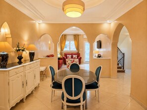 A dining area with a round table, chairs, and a white cabinet.