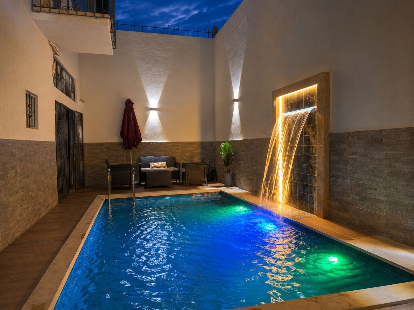 Une piscine intérieure agrémentée d’une cascade, d’un espace détente et offrant une vue sur le ciel.