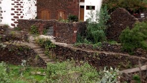 A rustic building with a stone facade and a red roof, surrounded by greenery and a stone wall. - Renovated stone house 6 minutes from Valverde (Mocanal)