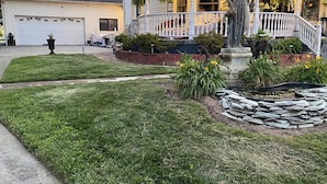A house with a circular porch, a statue, and a stone fountain.