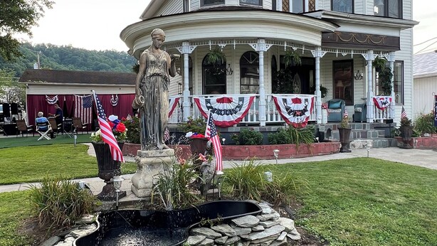 A large, historic house with a prominent turret, a fountain, and a well-maintained lawn.